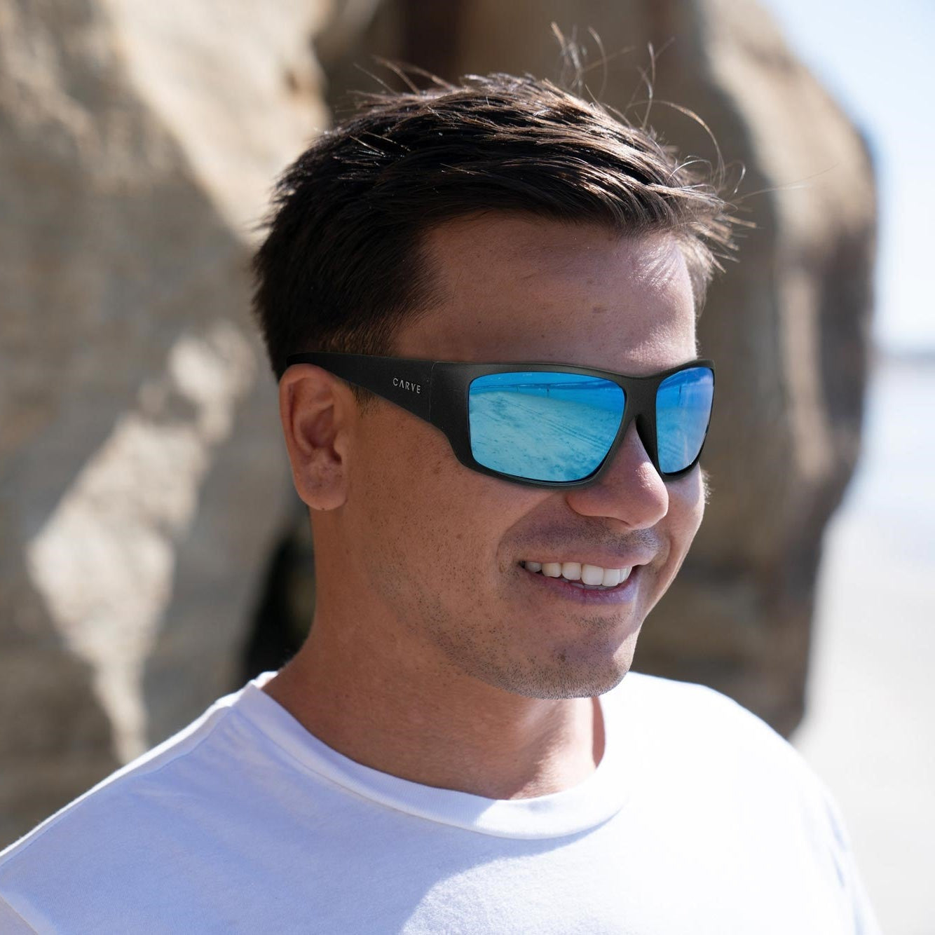 Man wearing sunglasses with a stone wall background