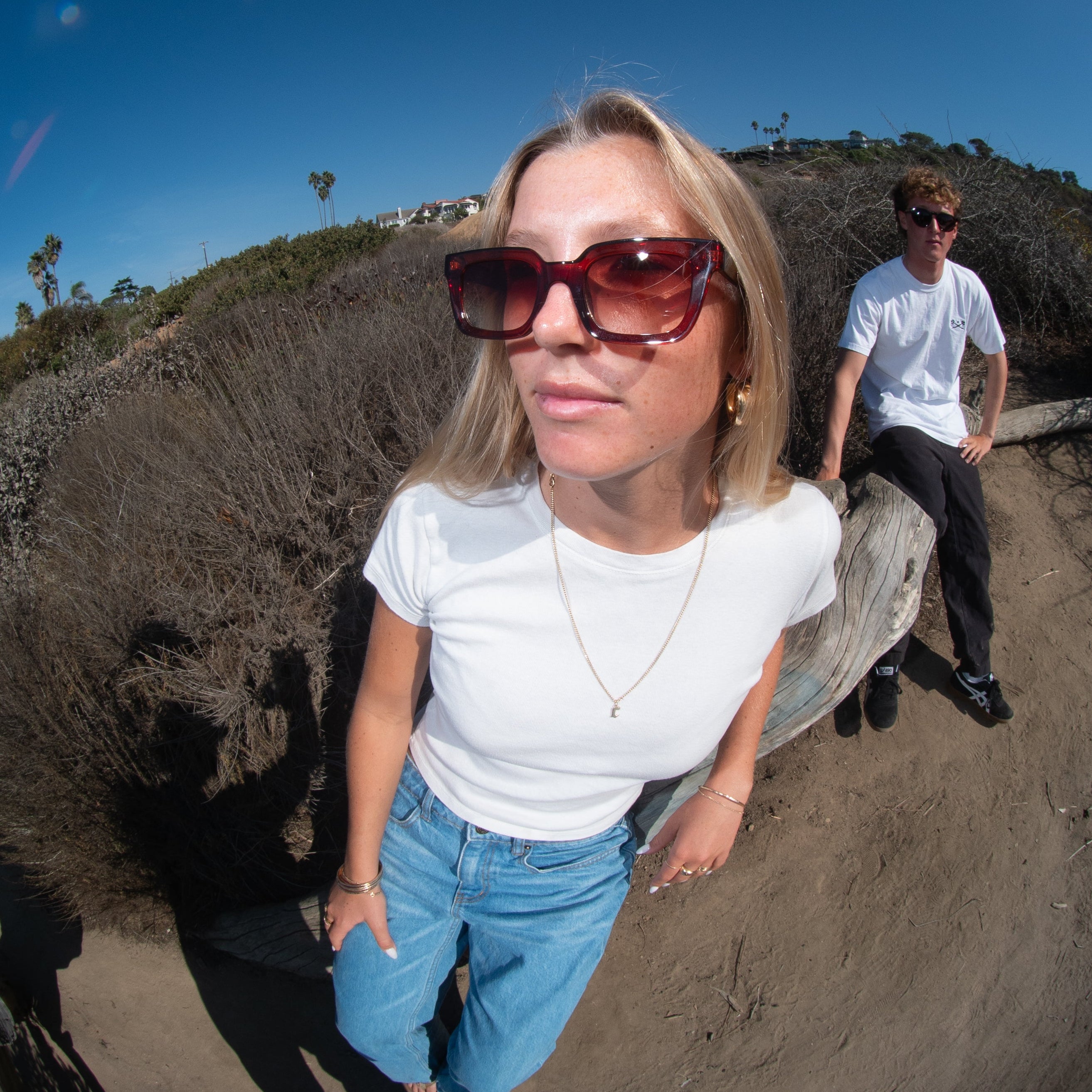 Two people standing on a hill with a clear blue sky, captured in a fisheye lens effect.