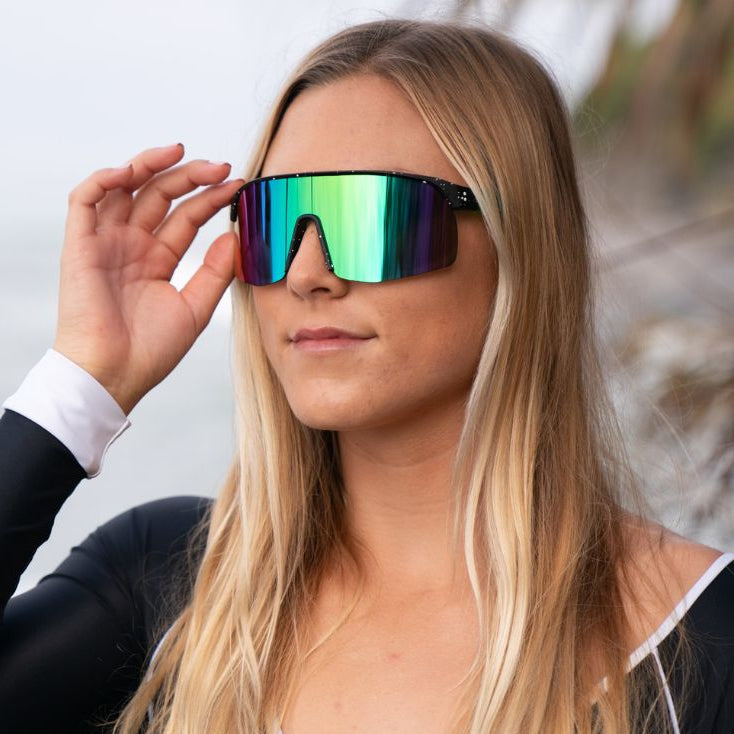 Woman wearing colorful reflective sunglasses with a blurred natural background