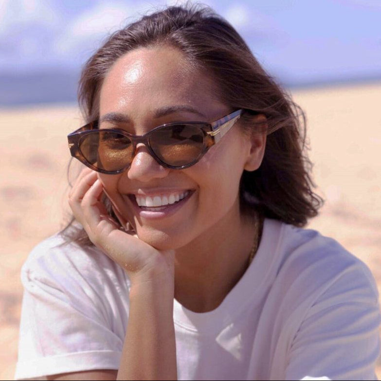 Woman wearing sunglasses and a white shirt on a beach