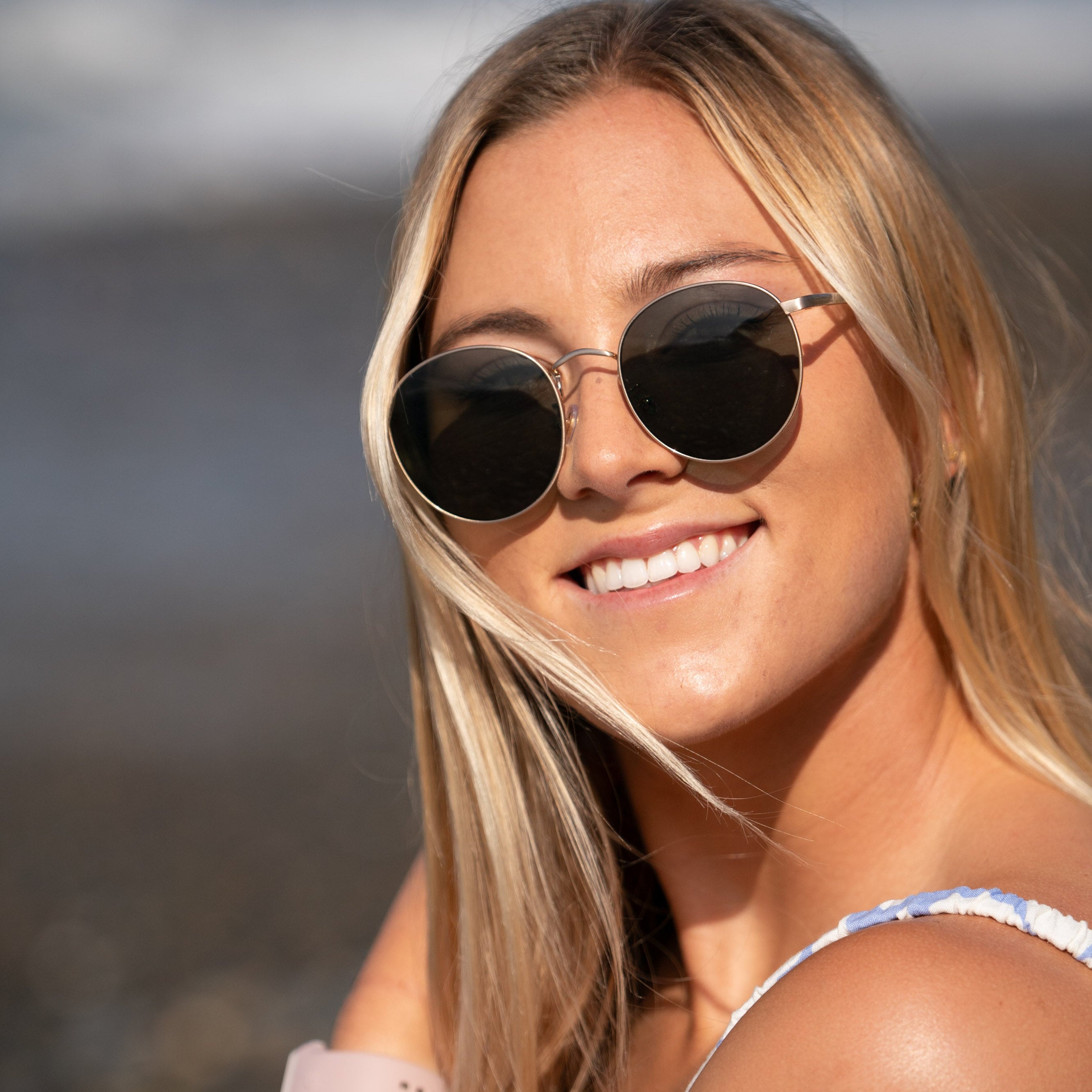 Woman wearing sunglasses with a blurred beach background