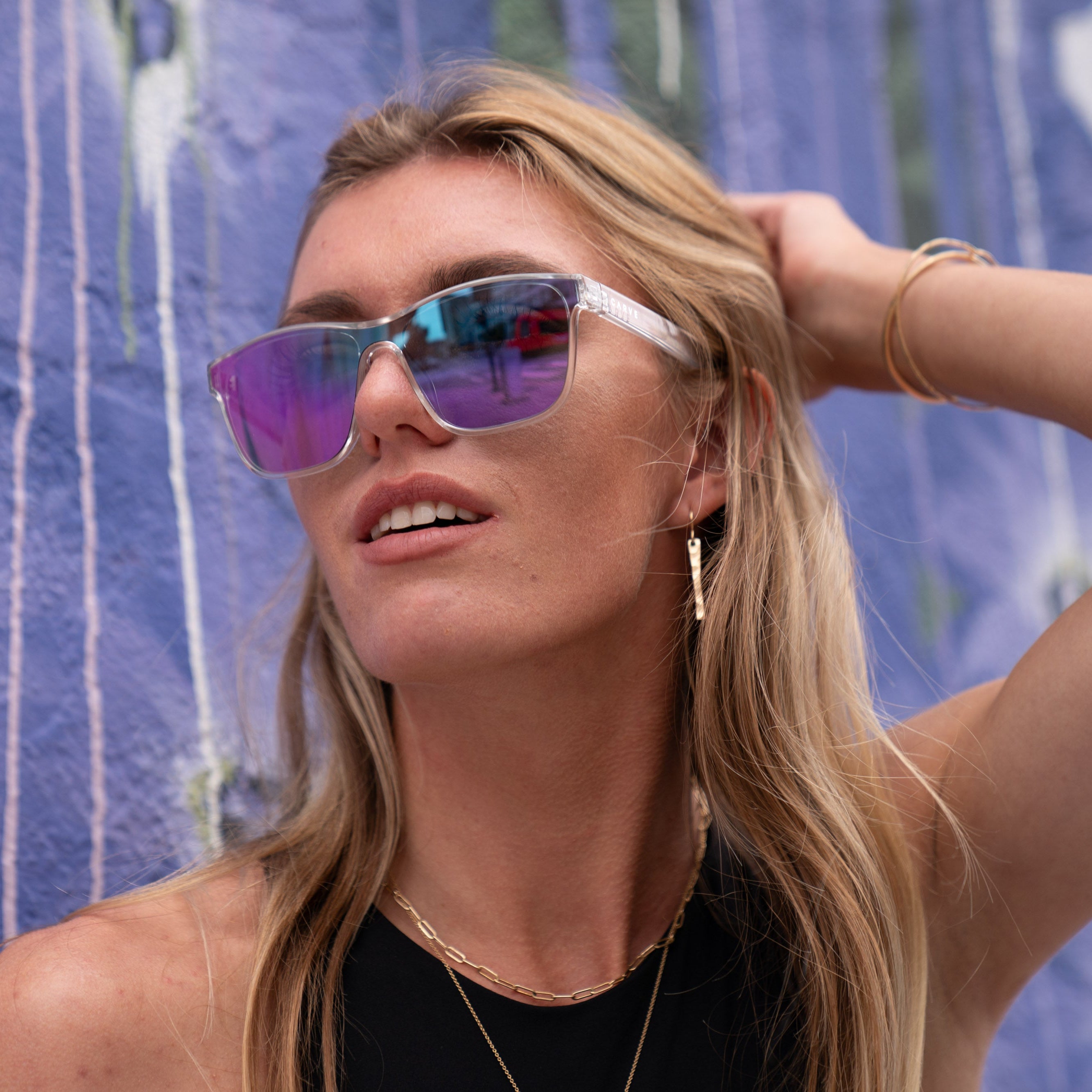 Woman wearing colorful sunglasses against a blue patterned background