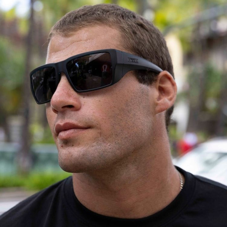 Man wearing black sunglasses with a blurred outdoor background
