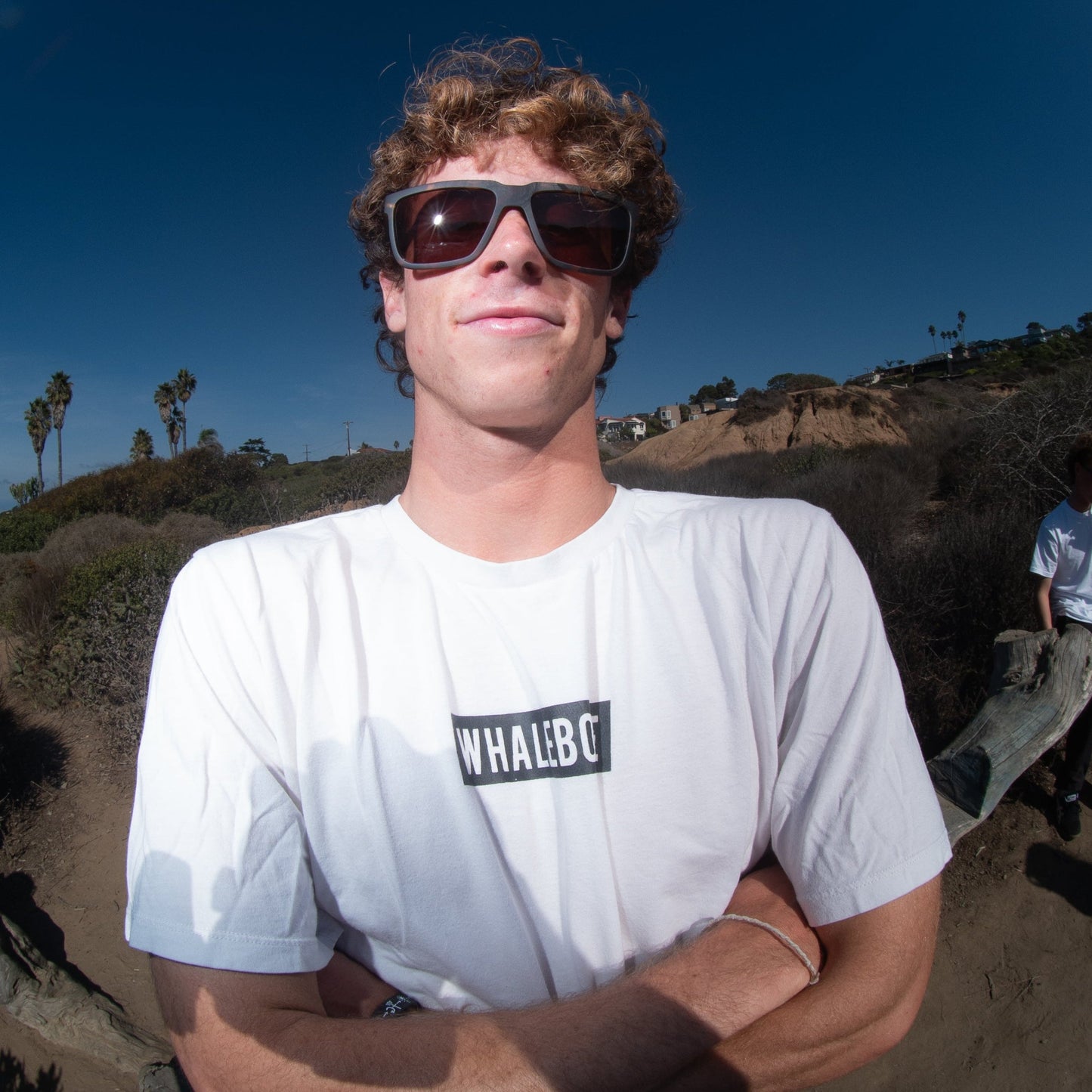 Man wearing sunglasses, standing on a coastal path.