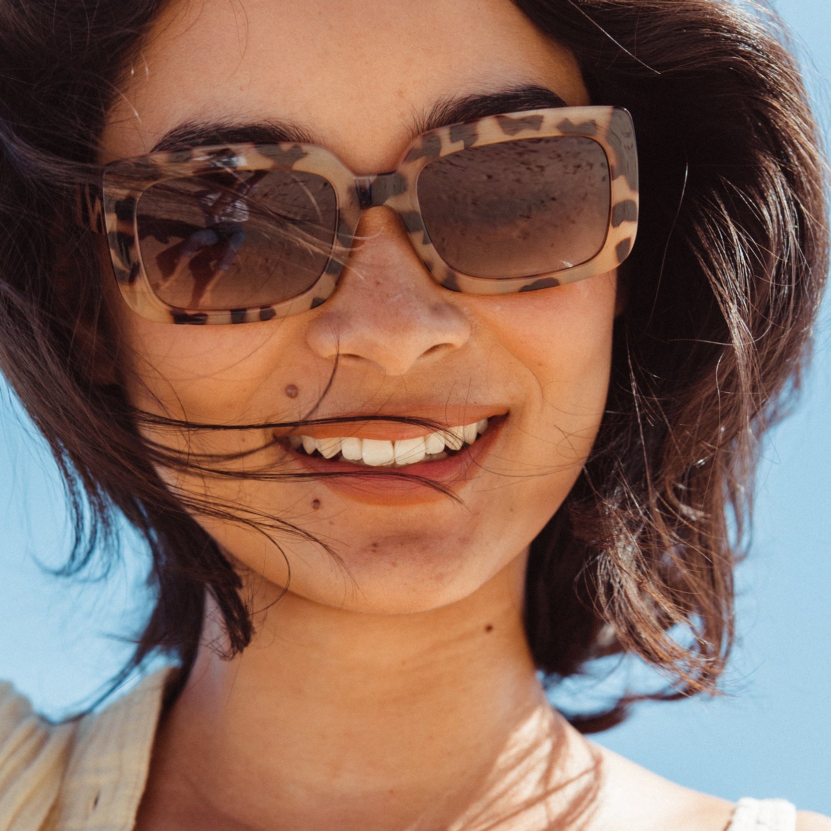 Woman wearing sunglasses with a blurred blue background