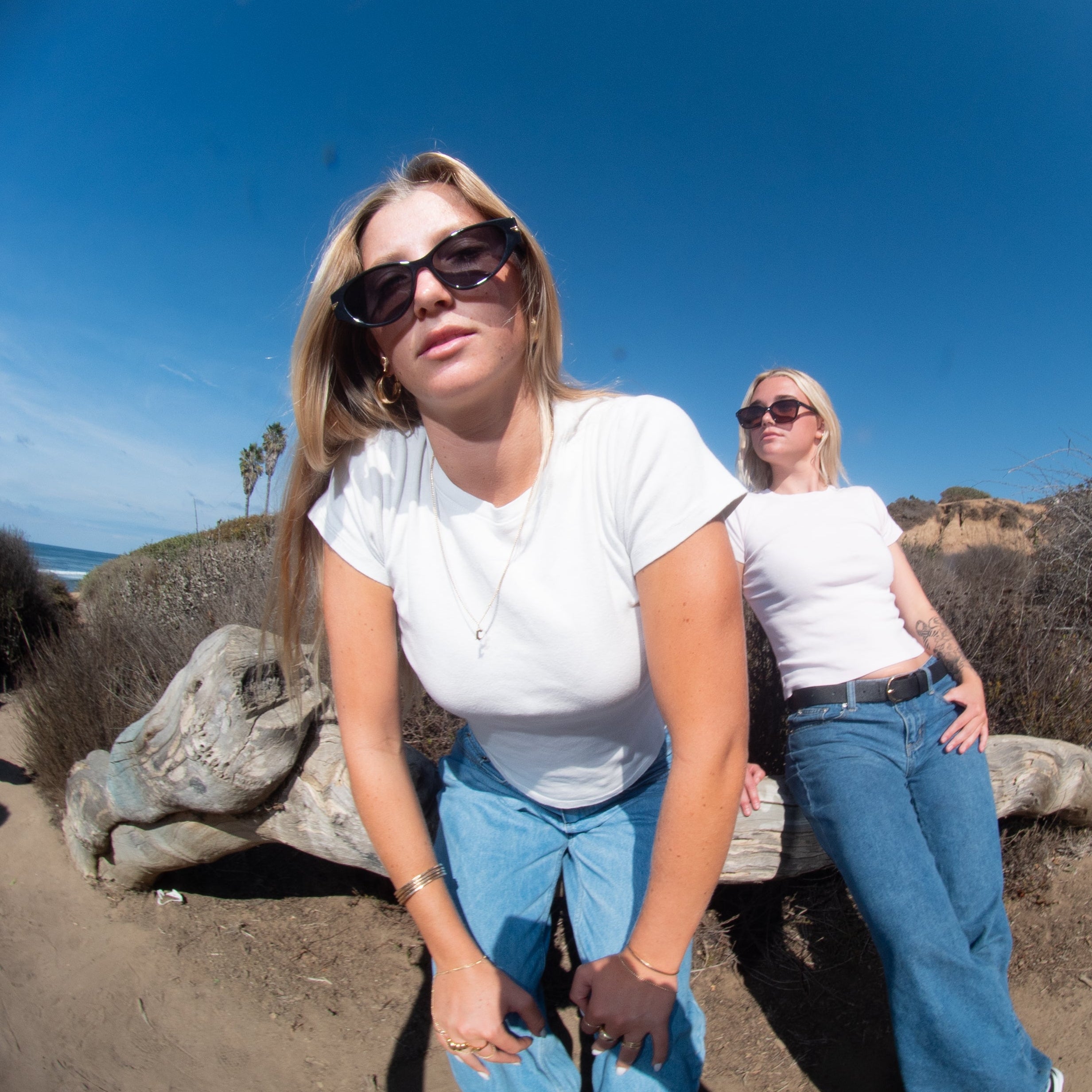 Two women standing on a beach with a fish-eye lens effect.