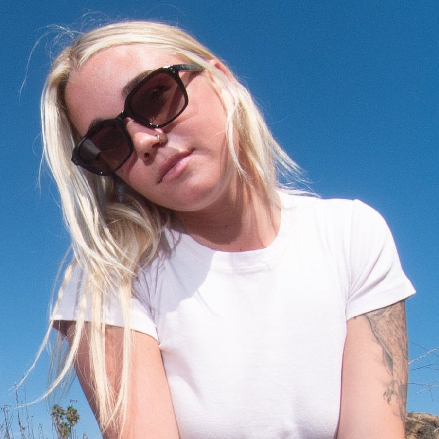 Woman in sungalsses posing outdoors with a fisheye lens effect.