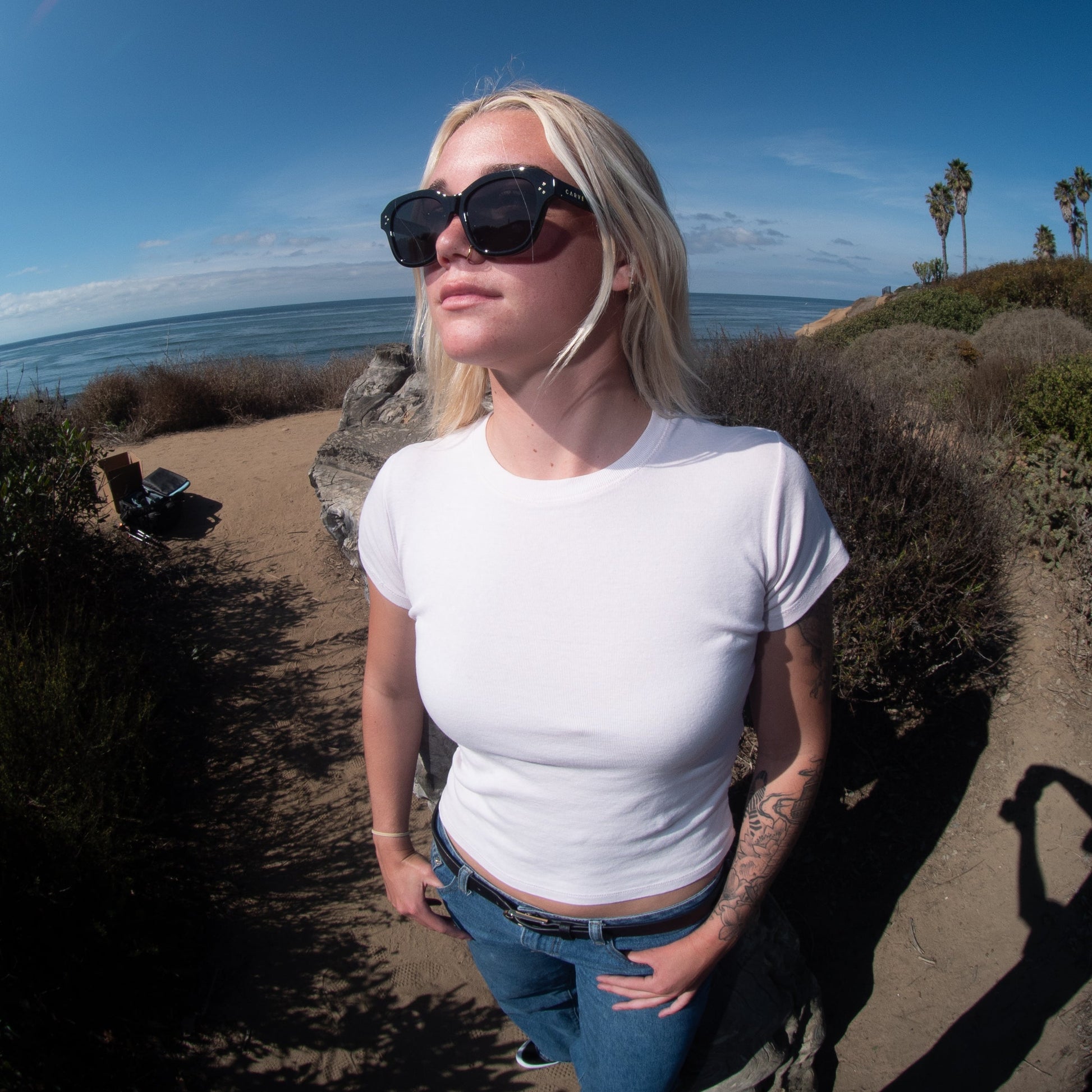 Person standing on a beach path with ocean and sky in the background