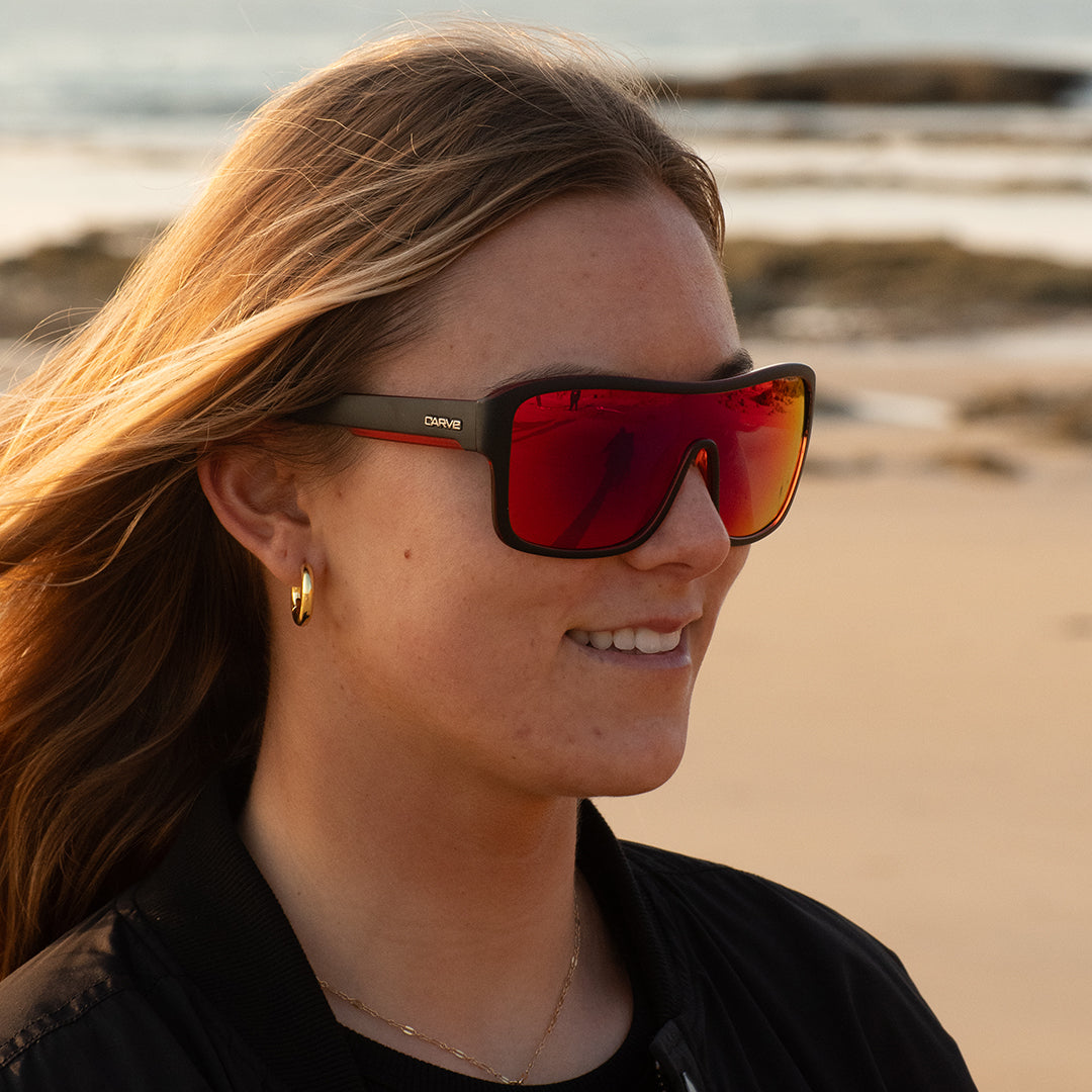 Person wearing red-tinted sunglasses on a beach