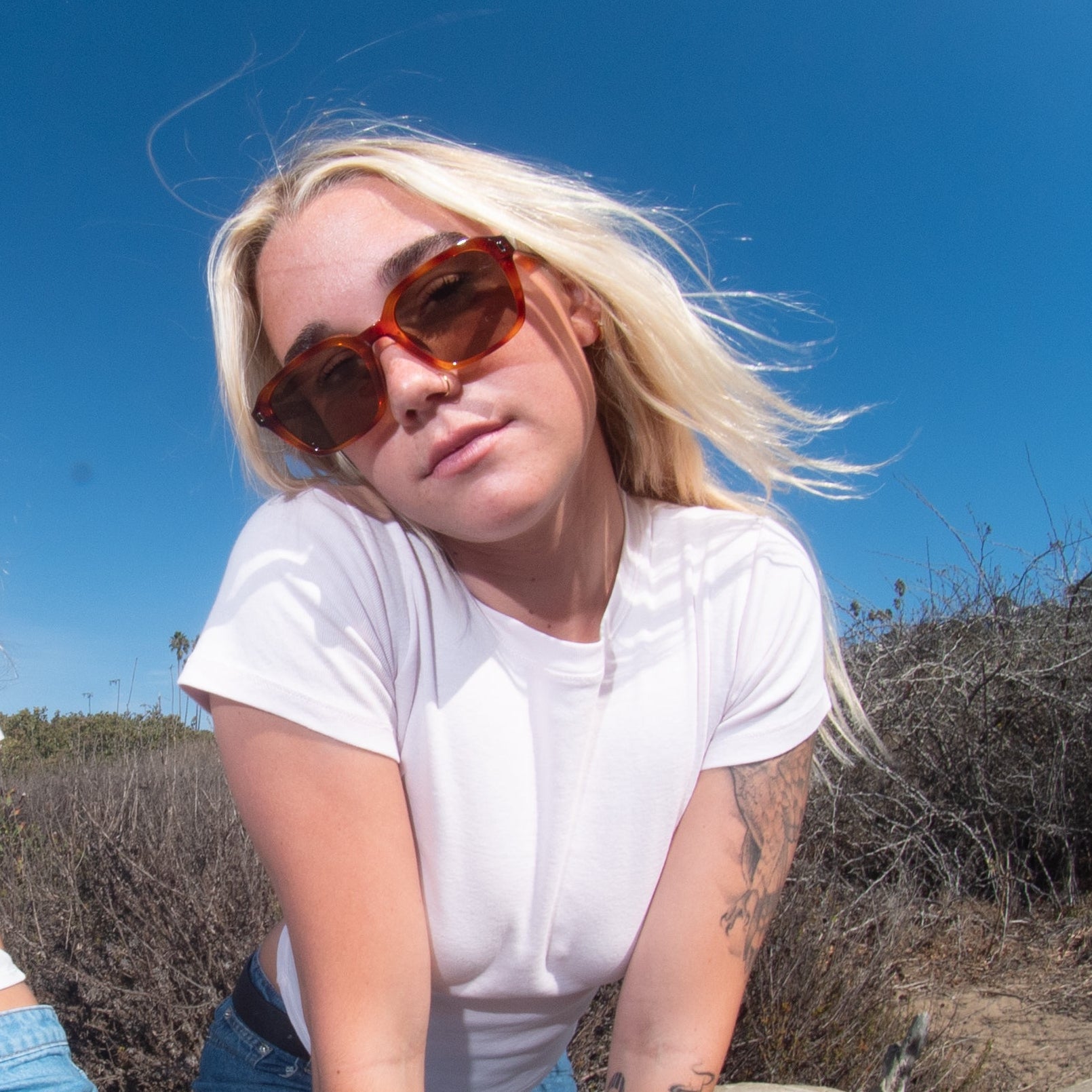 Two women posing on a beach with a fish-eye lens effect.
