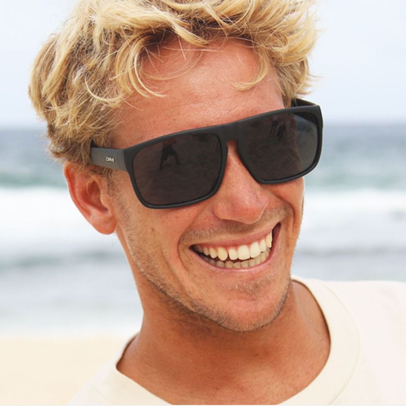 Man wearing sunglasses with a blurred beach background